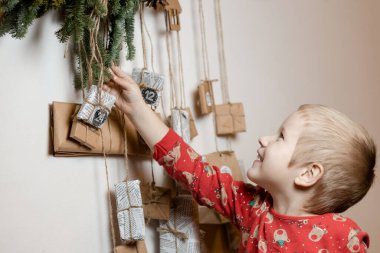 Gülümseyen küçük çocuk evde Advent takviminden hediye alıyor. Noel geleneği. Yüksek kalite fotoğraf