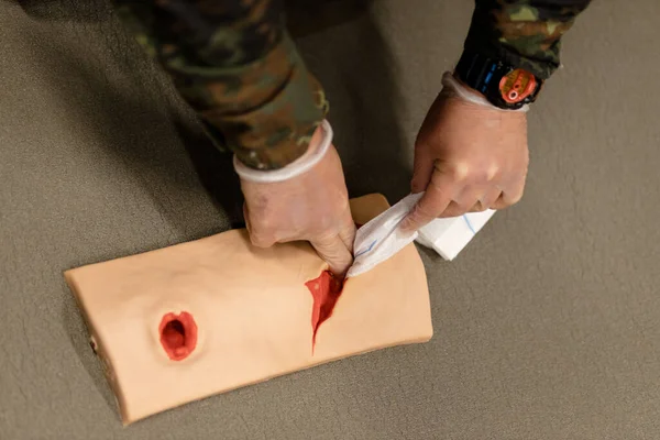 A military medic practices stopping bleeding on a wounded mannequin. High quality photo