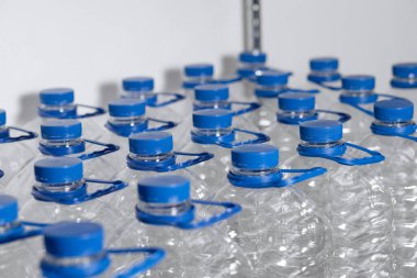Many empty water bottles with lids and handles are lined up in a display case. View from above. High quality photo