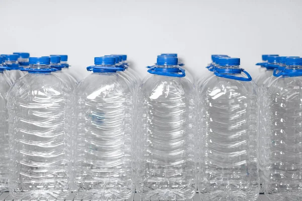 Many empty water bottles with lids and handles are lined up in a display case. High quality photo