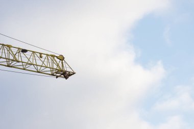 Part of a construction crane against a blue sky. Bottom view of an industrial crane. Concept of construction of multi-apartment buildings and housing reconstruction. Copy space. High quality photo