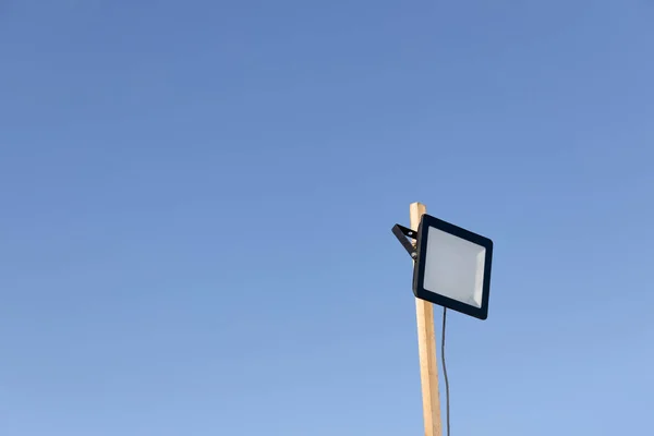 LED street lamp glowing on background of blue sky. Street home electric lantern fixed on wooden rail on sky background