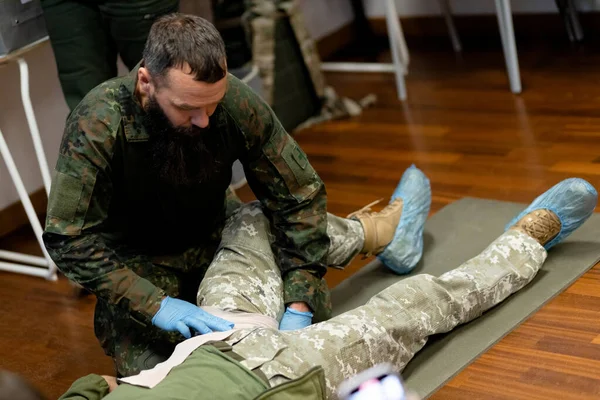 A 40-year-old bearded military medic demonstrates how to pack a wound to stop bleeding. Pre-medical training courses. High quality photo