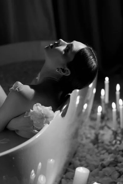 一个美丽的欧洲女人躺在一个有着白玫瑰和蜡烛的浴池里 黑白照片 高质量的照片 — 图库照片