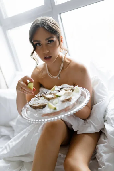 ホテルに座ってカキを食べ カメラを見て美しいセクシーなブルネットの女性 高品質の写真 — ストック写真