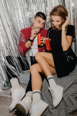  Spor ayakkabılı bir çift yerde oturmuş soda içiyor ve gümüş perdelere karşı eğleniyorlar. Yüksek kalite fotoğraf
