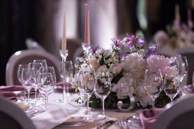 5 numaralı zarif düğün masası. Çiçek dekoru ve yemek takımı lüks bir ziyafet salonunda. Düğün kutlaması için sıcak ve davetkar bir ortam yaratıyor.