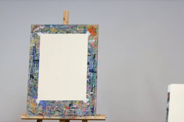 Ressamların dokunuşlarını boş bir tuval bekliyor. Tarafsız bir arkaplan üzerine boyanmış bir sehpanın üzerine kurulmuş..