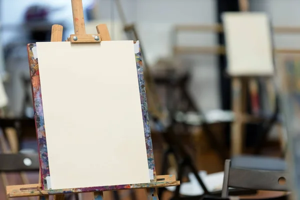 アートスタジオのカラフルなイーゼルに空白のキャンバス 絵画の準備ができて 背景に別のキャンバス — ストック写真