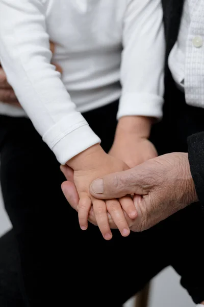 Close-up of two people holding hands, symbolizing support, unity, and generational connection