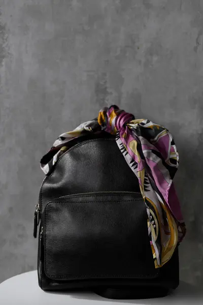 Una Elegante Bolsa Cuero Negro Con Una Bufanda Colores Atada Imagen de archivo