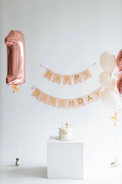 庆祝一周岁生日时装饰得很雅致的空间 有一个1形气球 一个Happy Birthday横幅 一个气球花束和一个白色底座上有一个顶子的蛋糕 — 图库照片