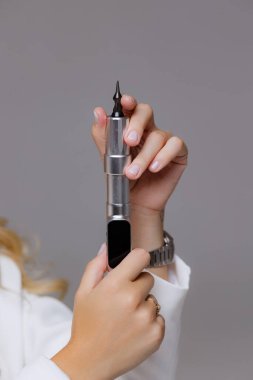 Uzman bir kozmetik uzmanının ellerini profesyonel bir aletle yakalar. Görüntü, güzellik ve estetiğe duyarlılık, beceri ve adanmışlık taşır.