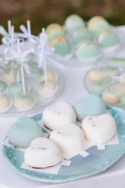 Yumuşak pastel renkte kalp şeklindeki tatlılardan oluşan bir seçim dekoratif bir tabakta düzenlenir, neşeli bir açık hava etkinliğinde hoş bir ziyafet sergilenir, kutlamalar için mükemmeldir..