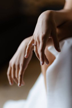 Zarif eller, yumuşak kumaşlardan oluşan, sevgi ve bağlılığın somutlaştırıcı anlarına karşı nazikçe parıldayan bir yüzük sergiliyor. Bu kompozisyonda sanatçılık zarafet ve samimiyeti vurgular..