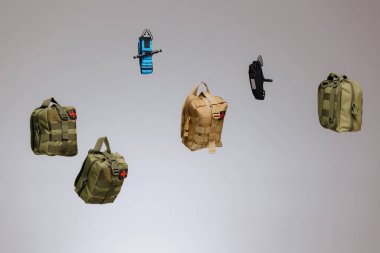 Taktiksel sırt çantaları ve aksesuarları bir macera ve hazırlık duygusunu çağrıştıran çeşitli tasarım, boyut ve renkleri gösteren sade bir arkaplan karşısında zarafetle süzülür..