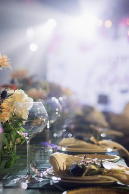 Çok güzel düzenlenmiş bir masa, canlı çiçekler ve kristal cam süsler sergiliyor ve unutulmaz bir kutlamaya zemin hazırlıyor. Yumuşak ışıklandırma toplanmanın büyüleyici atmosferini arttırır..