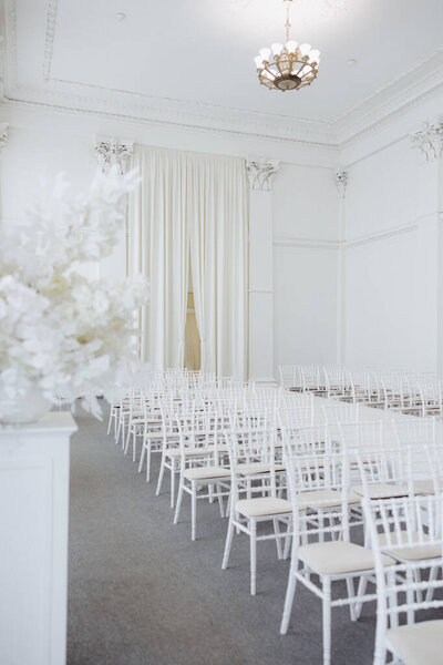 Это изысканное пространство имеет нетронутые белые стены, деликатные цветочные композиции и элегантные сидячие места, создавая очаровательную атмосферу для незабываемых событий.
