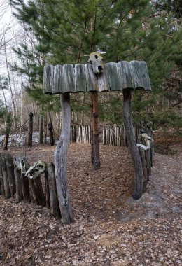 Keskinleştirilmiş ağaç gövdeleri ve güçlendirilmiş hayvan kafatasları ile çitli bölge diğer dünyayla iletişim için bir ayin yeri olarak hizmet vermektedir..