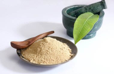 Havan topu, tokmak ve mango dolu bir tabakta beyaz renkli bir yüzeye bırakılmış Aamchoor Tozu.