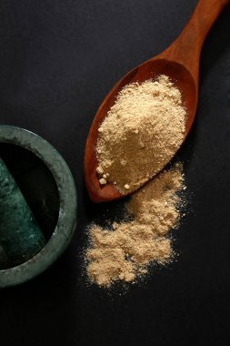 Siyah yüzey üzerinde kaşık içindeki Aamchoor Tozu