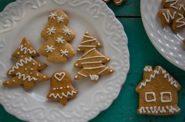 Geleneksel Noel zencefilli çörekleri beyaz tabaklara dizilmiş eski mahsul mahsuller masa, çeşitli Xmas şekilleri ağaçlar, evler ve kar taneleri.