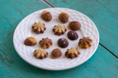 İki renk vanilyalı tarçın ve kakao aromalı geleneksel Noel sandviçleri eski boyanmış masadaki beyaz tabaklara dizilmiş çeşitli Xmas şekilleri.