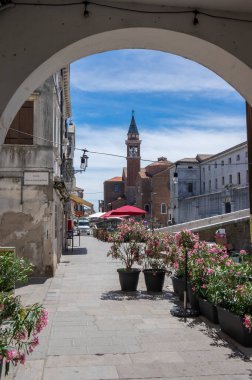 Chioggia, ITALY - 8 Haziran 2022: Chioggia şehrinin su kanalı, tekne ve güneş ışığı altında eski ilanları olan Pictoresque caddeleri