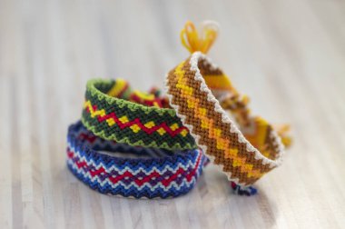 Group of handmade homemade colorful natural woven bracelets of friendship isolated on white striped background