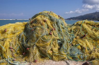 Fishermans equipment lying on the coastline in harbor, heap nylon yellow tangled fishing net in greece sunlight