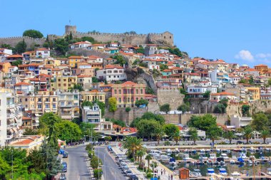 Arka planında Bizans şatosu olan Kavala 'nın eski kasabası, palmiye ağaçları, gezinti güvertesinde yayalar ve önünde tekneleri olan limanlar. Kavala kasabası, Makedonya, Yunanistan.