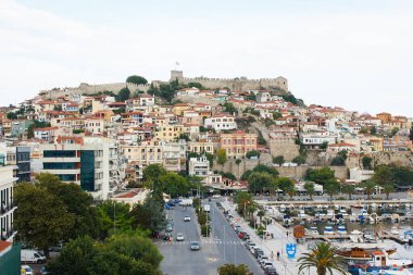 Arka planında Bizans şatosu olan Kavala 'nın eski kasabası, sokağın yanında modern tarz evler ve önünde balıkçı tekneleri olan liman. Kavala kasabası, Makedonya, Yunanistan. 