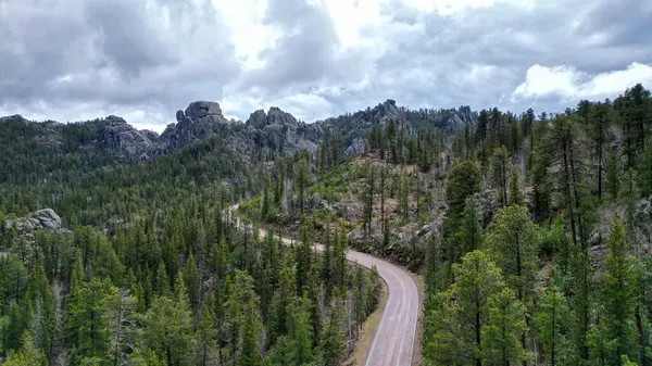 Kayalık dağlarda dolambaçlı bir yol. Drone atışı, otoyolun havadan çekilmiş fotoğrafı ulusal parktan geçiyor. Orman manzarası
