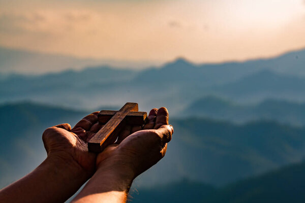 Humans raise their hands in prayer and worship the cross with fa