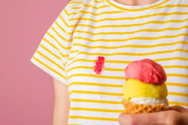 İzole edilmiş bir tişörte kremalı çilekli dondurma döken bir kadın. Pembe bir arka planda. Yüksek kalite fotoğraf