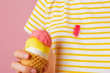 Elbiselerindeki kirli çilekli dondurma lekesi. Dişilerin elinde üç kepçe farklı aromalı dondurma külahı. İzole. Sarı arka planda. Yüksek kalite fotoğraf