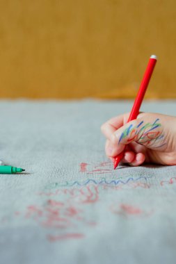 Mürekkep ellerle boyanmış bir çocuk, kanepenin döşemesine kırmızı bir işaret çiziyor. Mobilya kumaşı. Temizlik konsepti. Yüksek kalite fotoğraf