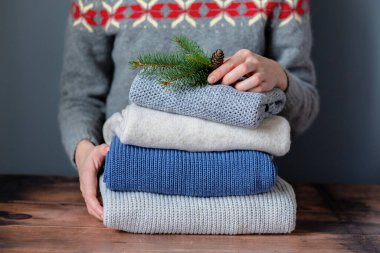 Yığınla giysi üzerinde makyaj yapan kadın eller, tahta bir masanın üzerinde koni ile bir Noel ağacı dalı tutuyor. - Evet. Yüksek kalite fotoğraf