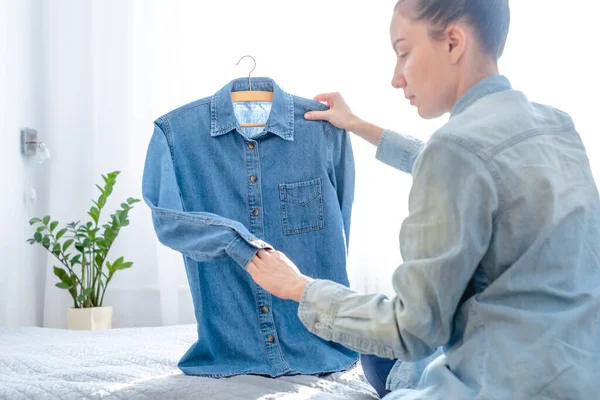 A girl examining clothes for sell online, sitting on the bed at home. Resale go clothes. Slow fashion concept. Conscious and environmentally consumption. Zero waste. High quality photo