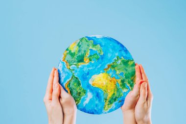 Mother and son holding a painting of the Earth on a blue background. Save the planet. High quality photo
