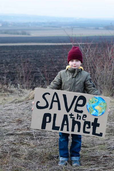Eco activist boy holding save the planet banner. on the background of arable land. Farmland preservation concept. High quality photo