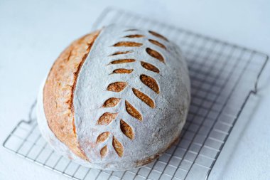 Close up homemade organic bread on the grid. Crispy unleavened sourdough bread on a white table. Healthy food. High quality photo