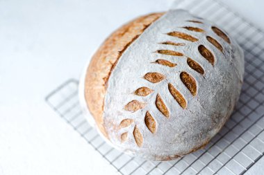 Close up homemade organic bread on the grid. Crispy unleavened sourdough bread on a white table. Healthy food. High quality photo