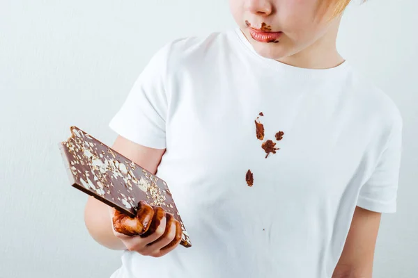 Dirty chocolate stain on clothes. A boy is holding a bitten bar of chocolate. isolated, on a white background. daily life stain concept. High quality photo