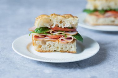 Jambonlu, domatesli, ıspanaklı, peynirli ve bir tabakta Focaccia ile yapılan roka soslu sandviç. İtalyan ekmeği.. 