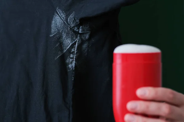 Mancha Desodorante Camisa Negra Fondo Una Mano Sosteniendo Desodorante Rojo — Foto de Stock