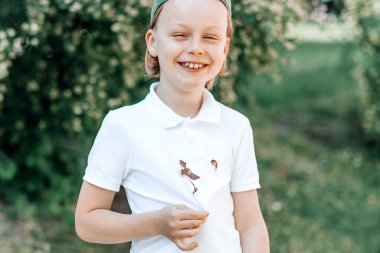 Yüzünde çikolata lekeleri olan beyaz elbiseli bir çocuğun portresi. Günlük yaşam lekesi konsepti. Açık havada. Yüksek kalite fotoğraf