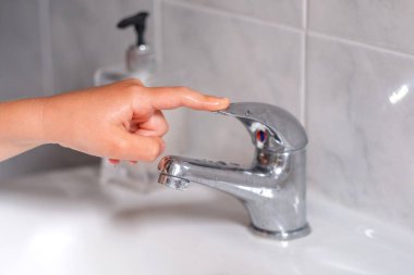 Çocuk hijyenik prosedürlerden sonra musluğu kapattı. Bu kavram suyu ve çevreyi korur. Yüksek kalite fotoğraf