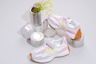 Teneke kutularda, arka planda çiçekler olan güzel, sıradan ayakkabılar. Sürdürülebilir ayakkabılar. Modern kadın ayakkabıları, spor ayakkabıları. Şık, şık spor ayakkabılar. Yüksek kalite fotoğraf. 