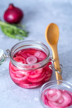 Cam kavanozda kırmızı soğan turşusu ve gri arka planda tahta bir kaşık. Aperatif, sos ya da sos. Sağlıklı mayalanmış yiyecek. - Evet. Yüksek kalite fotoğraf